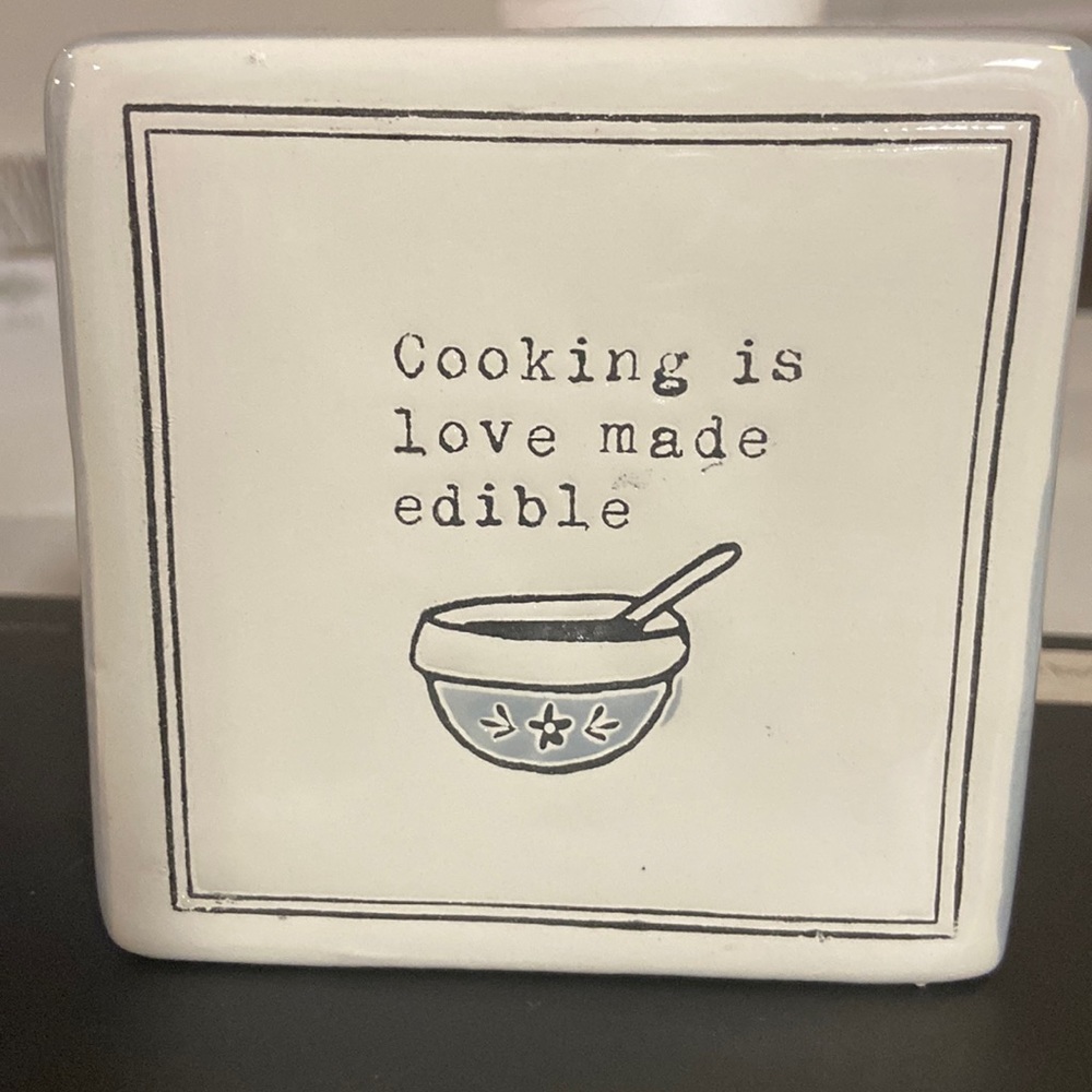 Glass sign that says “Cooking is love made edible”